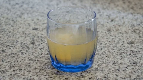 Effervescent Vitamin C tablet dropping and dissolving into a glass of water Stock Footage 123089003