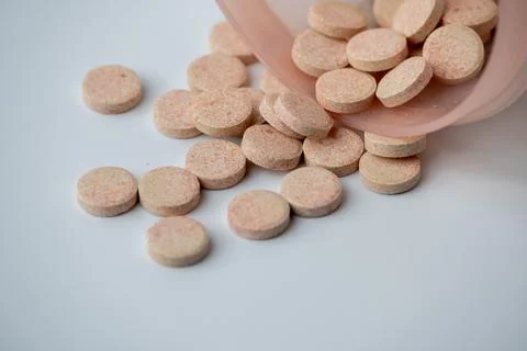 Effervescent Vitamin C Tablets Spilling from Container on White Background Stock Photos
