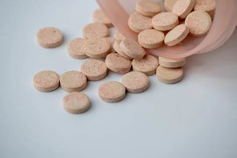 Effervescent Vitamin C Tablets Spilling from Container on White Background Stock Photos