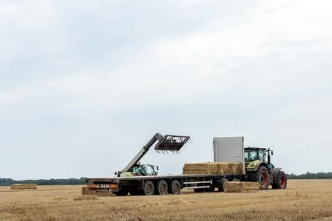 Efficient Farming Techniques: A Tractor and Loader at Work Collecting Hay Bales Stock Photos