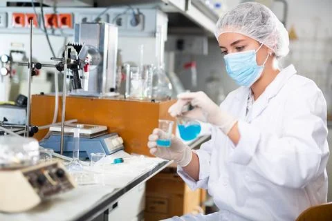 Efficient female lab technician working with reagents in test tubes during Stock Photos
