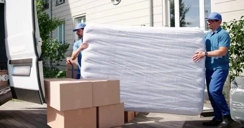 Efficient Movers Transport Mattress During Moving Day Delivery. Happy Workers Stock Photos