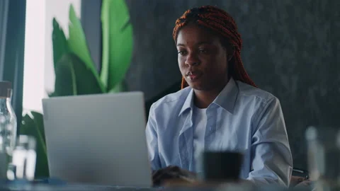 Efficient remote work: Black woman typing away at her laptop while sipping Stock Footage 239268468