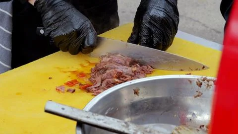 Efficient vendor prepares thin beef slices swiftly, Food vendor swiftly slices 스톡 사진
