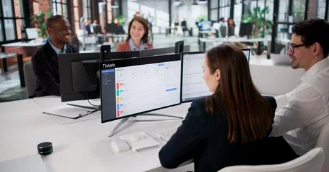 Efficient Young Man Installs Computer Software System For Diverse Team. Stockfoto's