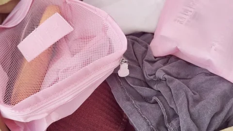 Efficiently packing a travel bag with clothes and pink organizers for a jou.. Vídeos de archivo 334552061