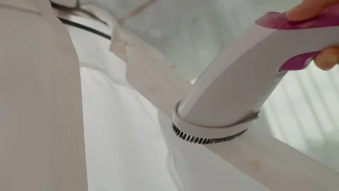 Efficiently smoothing clothes with a handheld steamer in a home setting Stock Footage 324649134