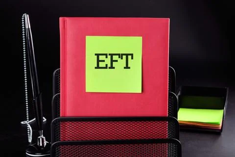 EFT Text on a yellow sticker on a red vertical notepad on a black backgroun.. Stock Photos