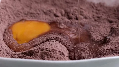 Egg adding to brown cocoa powder Stock Footage 249938027