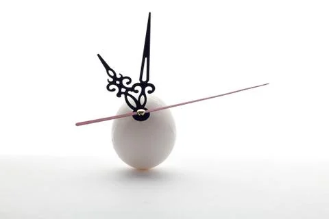 Egg and clock hands on white background Photos