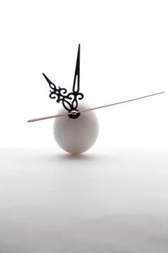 Egg and clock hands on white background Stock Photos