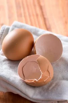 Egg and eggshells on the kitchen dishtowel with natural moody backlight 스톡 사진