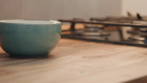 Egg and hand approaching bowl. Closeup of egg beside ceramic dish with hand Stock Footage 337453349