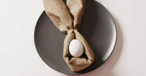 Egg and ribbon in shape of rabbit on plate on white background Stock Footage 331307177