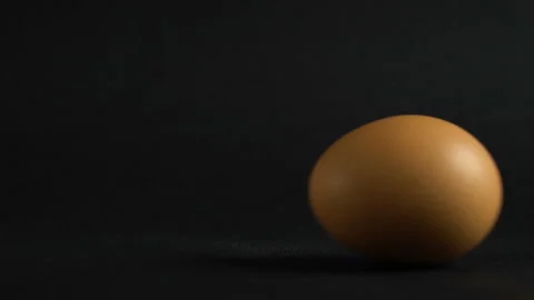 Egg are slowly rolling on the black table. Easter eggs background. Close up. Video stock 104855823