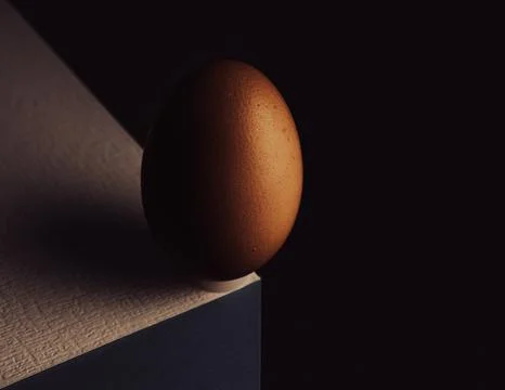 Egg, balancing on table edge. Minimalistic egg stands on colorful table sof.. Stock Photos