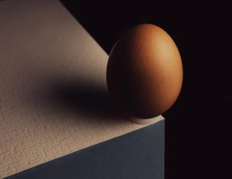 Egg, balancing on table edge. Minimalistic egg stands on colorful table sof.. Stock Photos