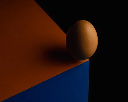 Egg, balancing on table edge. Minimalistic egg stands on colorful table sof.. Stock Photos