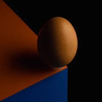 Egg, balancing on table edge. Minimalistic egg stands on colorful table Stock Photos