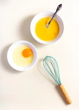 Egg beat, Egg Shell with Whisk. Raw eggs in a glass and white bowl on the t.. Stock Photos