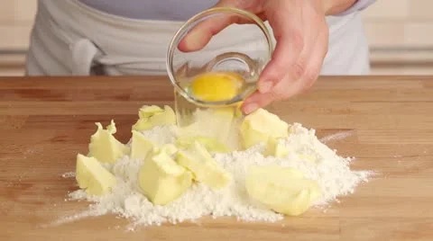An egg being added to a pile of flour and butter Stock Footage 24669639