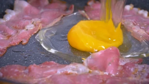 Egg being dropped on fried bacon in slow motion 스톡 동영상 89619323