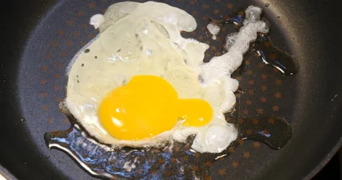 Egg being dropped in a frying pan on cook Vidéo 162615039