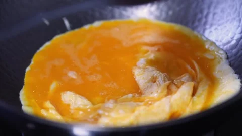 An egg is being fried in a wok, stirred by a metal ladle. 库存影片 333313086