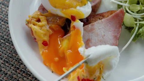 Egg Benedict is elegantly broken, revealing the luscious yolk within. The rich Video stock 248580583