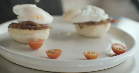 Egg Benedict with ham, cherry tomatoes and potatoes. 4K video in slow motion Stock Footage 103576516