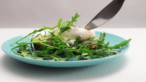 Egg Benedict,the knife cuts the egg on the avocado toast, the yolk flows ou.. Stock Footage 252021266