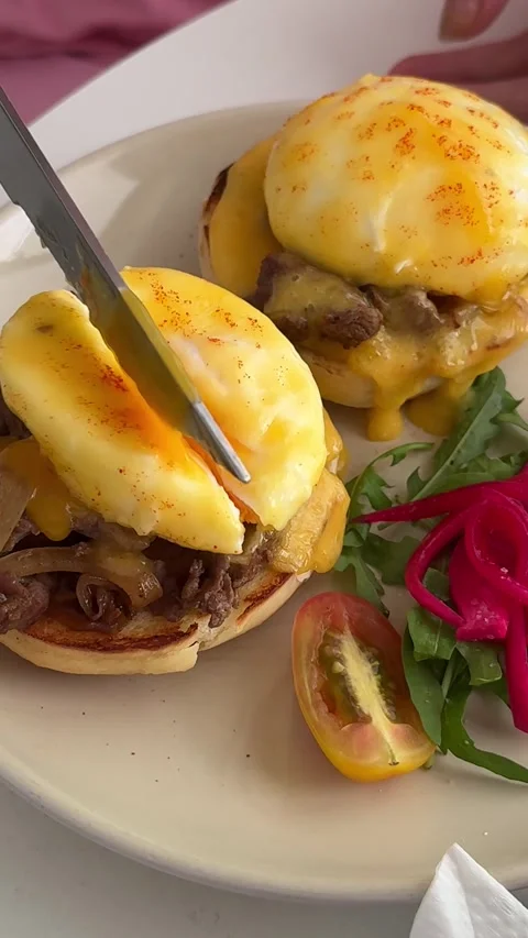 Egg Benedict sandwich eating fried eggs with a bread on a green plate. close-up Stock Footage 313741718