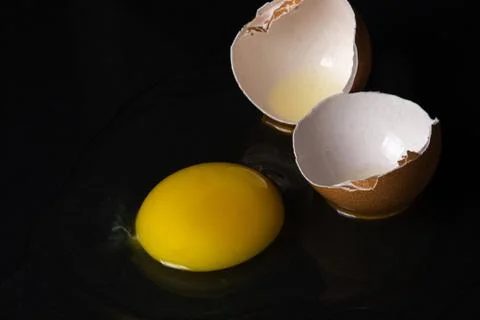Egg on a black background. Broken chicken egg.  Stock Photos