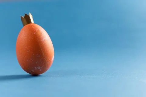 Egg on a blue background. Close-up plan. An egg in the image of a king with a Stock Photos