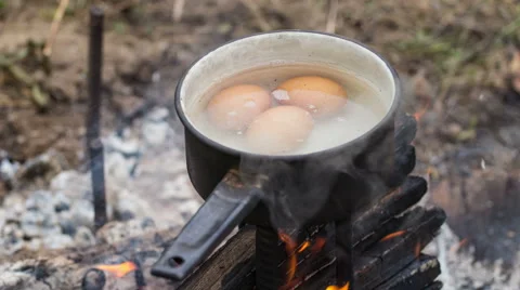 Egg in a boiling water on a camping fire. Time lapse Stock Footage 54528389