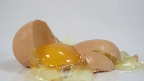 Egg breaking after being dropped to reveal broken shell and egg yolk Stock Footage 72513299