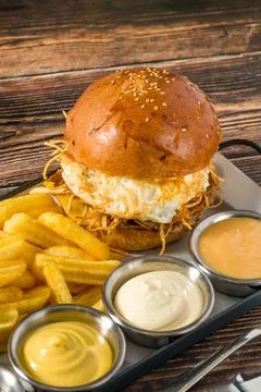 Egg burger with crispy potatoes served with fries and sauces Stock Photos