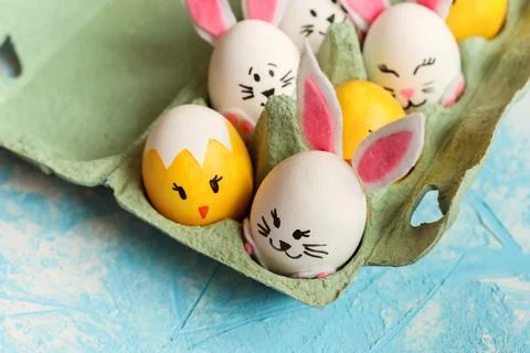 Egg carton with Easter decorative eggs, painted as chicks and bunnies. Close up. Stock Photos