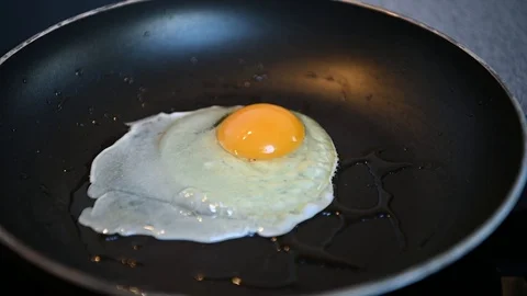 Egg Cooking In A Greasy Pan In Slow Motion Stock Footage