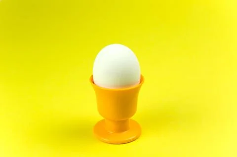 Egg in cup at yellow background Stock Photos