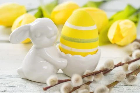An egg cup with a yellow easter egg and tulips 스톡 사진