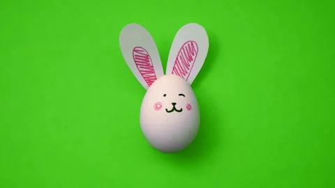Egg with cute bunny face and ears on green background. Happy Easter Stock Footage 300741030