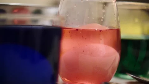 Egg dropping in slow motion in glass of pink dye holiday season Stock Footage 151503611