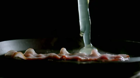 Egg Drops On Bacon In A Pan While Cooking Vídeo Stock 147635760