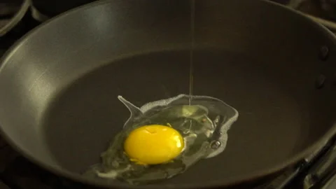 Egg drops onto frying pan Stock Footage 201011391