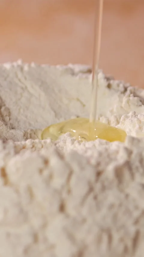 Egg Drops Into Mound Of Flour During Bread Baking Process. Clear Albumen Streams Stock Footage 346764338