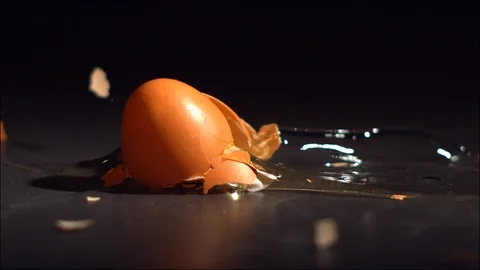 Egg falling and breaking  in slow motion on black tile surface. Stock Footage 129335094