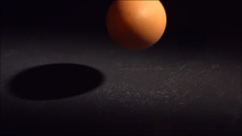 Egg falling and breaking  in slow motion on black tile surface. Stock Footage 129335238