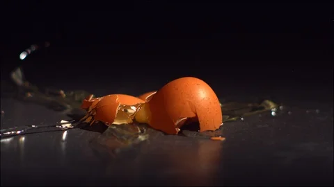 Egg falling and breaking  in slow motion on black tile surface. Stock Footage 129335262
