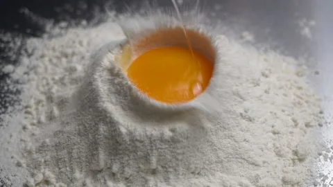 Egg falling into flour, Close-up and slow motion Stock Footage 132678599